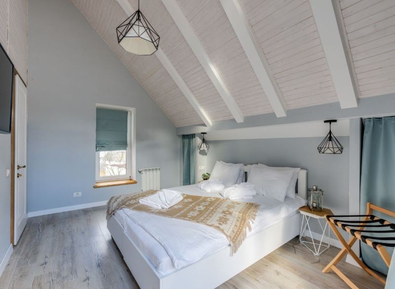 Zieleń, brąz i biel to kolory, które nadają rustykalnej sypialni sielski klimat.